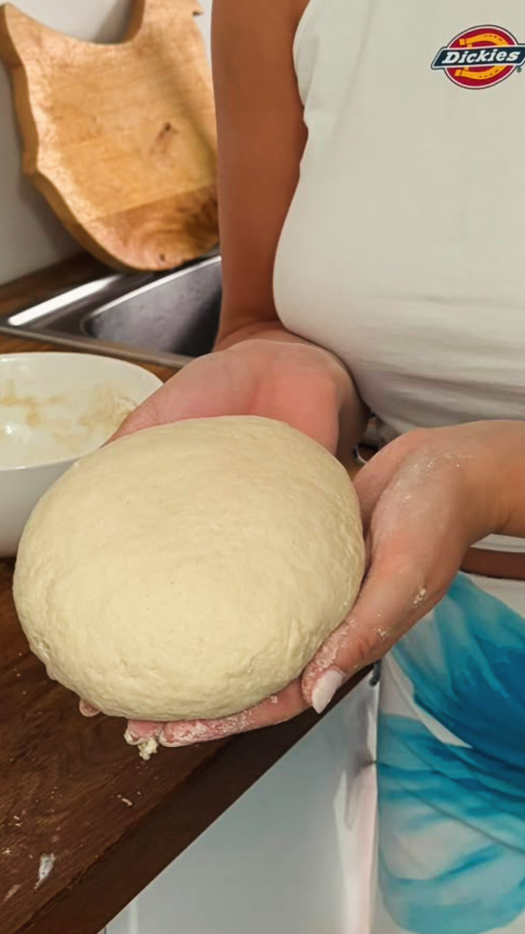 Deux mains présentent un pâton de pâte à pain tout juste pétri